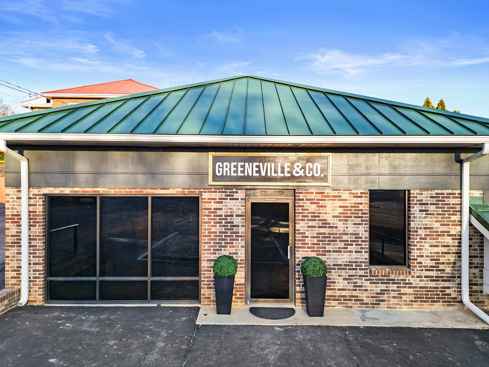The Greeneville & Co. office on Tusculum Boulevard, a brick building with a green standing-seam roof and the company sign above the door